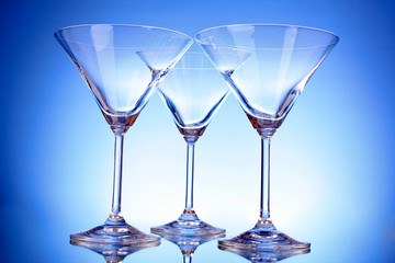 Three empty martini glasses on blue background