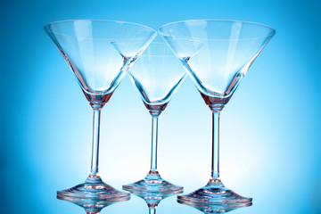 Three empty martini glasses on blue background