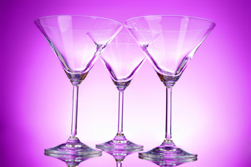 Three empty martini glasses on purple background