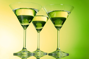 Three martini glasses on green background