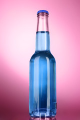 Bottle with alcohol on pink background
