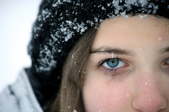 Closeup photo of little girl face in snow, half