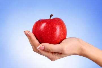 An apple on the hand on blue background