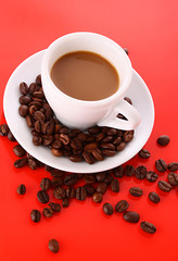 Small white cup of coffee with coffee grain  on red background