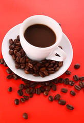 Small white cup of coffee with coffee grain  on red background