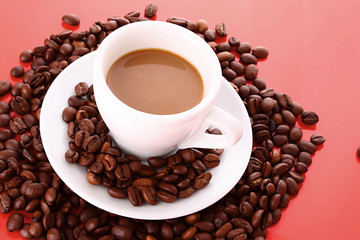 Small white cup of coffee with coffee grain  on red background