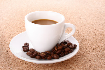 Small white  cup of coffee with coffee grain   on brown backgrou