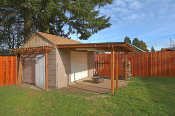 Fototapeta na wymiar Beige small shed in the fenced back yard