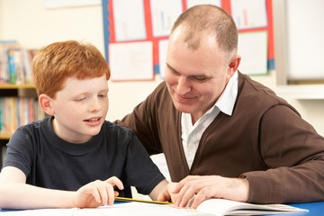 Naklejka premium Male Pupil Studying in classroom with teacher
