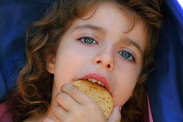 Little girl eating biscuit closeup portrait