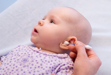 cleaning ear of baby with cotton swabs - obrazy, fototapety, plakaty