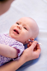 cleaning ear of baby with cotton swabs - obrazy, fototapety, plakaty