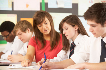 Teenage Students Studying In Classroom With Teacher