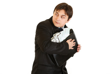 Wary businessman hugging briefcase with money in hands