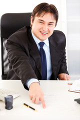Smiling  businessman pointing on document for signature.