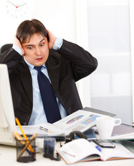 Shocked businessman  being overloaded with loads of work .