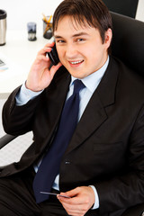 Smiling  businessman making purchase by phone and credit card.