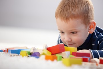 Adorable ginger-haired boy playing with cubes
