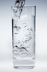 Pouring mineral water stream into a glass