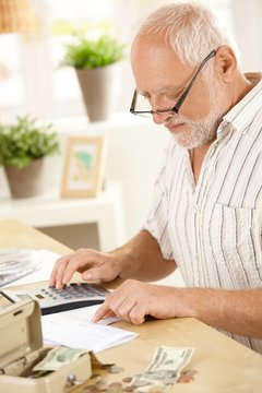 Older man using calculator at home