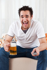 young boy watching the television and holding a glass of beer