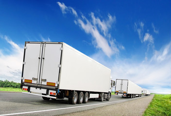 caravan of white trucks on highway under blue sky