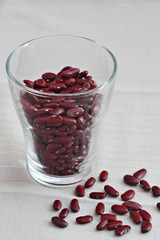 Red beans in a glass pot on a light linen cloth.