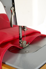 Sewing machine is stitching red fabric