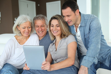 Portrait of happy family sitting in sofa with electronic tablet