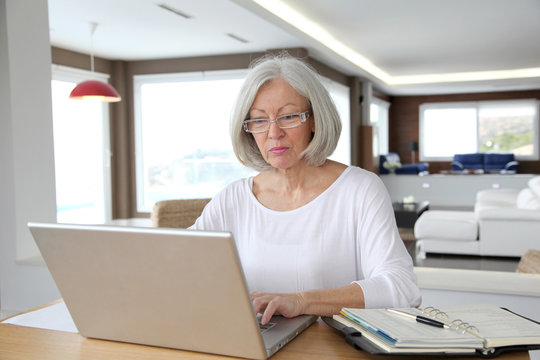 Senior woman at home in front of laptop computer