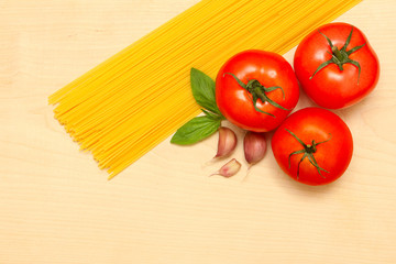 pasta, garlic, tomatoes and basil on a wooden board