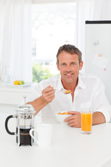 Fototapeta na wymiar Handsome man having his breakfast in the kitchen