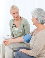 Obraz premium Lovely doctor taking the blood pressure of her patient