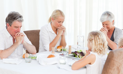 Obraz na płótnie Canvas Pretty family praying at the table