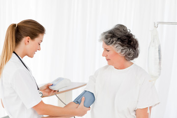Obraz premium Nurse taking the blood pressure of her patient