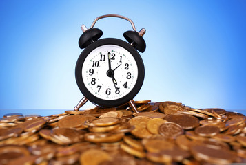 Alarm clock with golden coins on blue background