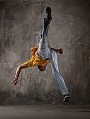 Obraz na płótnie Canvas Young man jumping against grunge wall