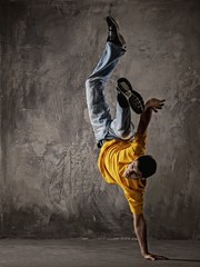 Young man dancing against grunge wall