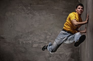 Young man dancing against grunge wall