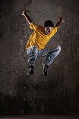 Fototapeta na wymiar Young man jumping against grunge wall