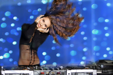 The beautiful girl in headphones dances near DJ panel