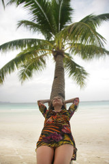 young woman resting on palm tree on sea background