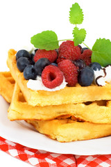 Tasty waffles with fruits, whipped cream and chocolate.