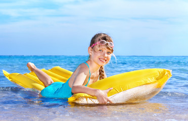 Child swimming on inflatable beach mattress.