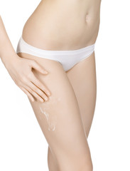 Slim girl spreads cream on her leg, isolated on white background