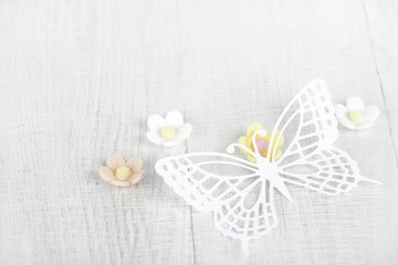 paper butterfly and three sugar blossom flowers on white old tab