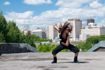Beautiful girl dancing hip-hop over urban landscape
