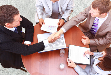 handshake over paper and pen,blurry computer in the