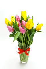yellow and pink tulips in a glass tied with a red bow