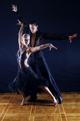 dancers in ballroom against black background